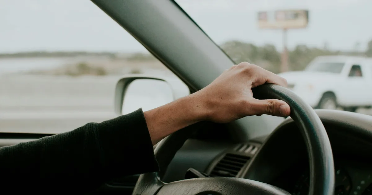 A driver at the wheel of a car, seen from the passenger seat