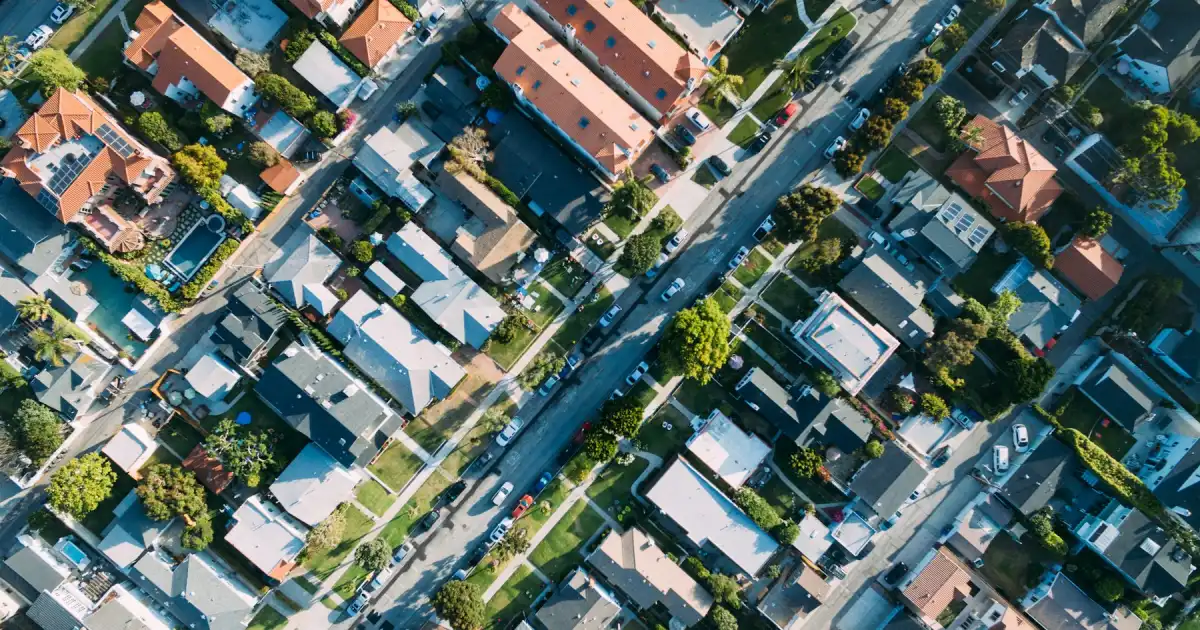A drone view of a suburb, its streets and houses laid out in blocks