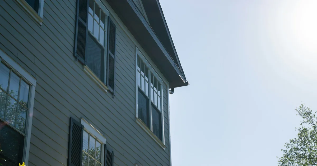 A grey house with black shutters seen from the street