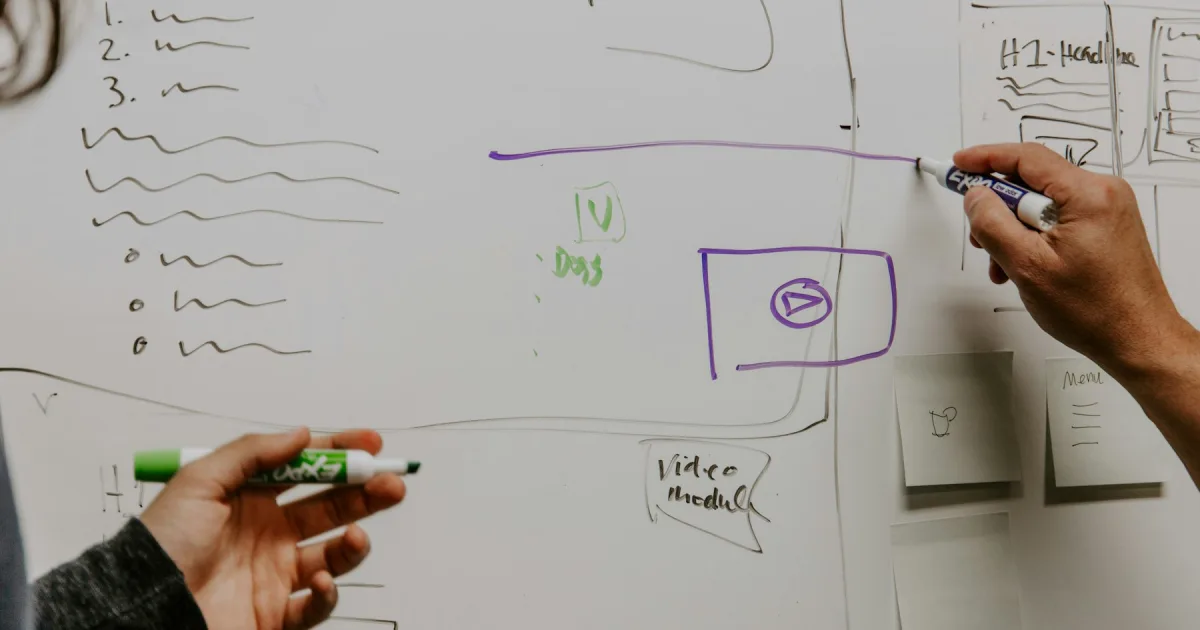 Two people mapping out a process on a whiteboard