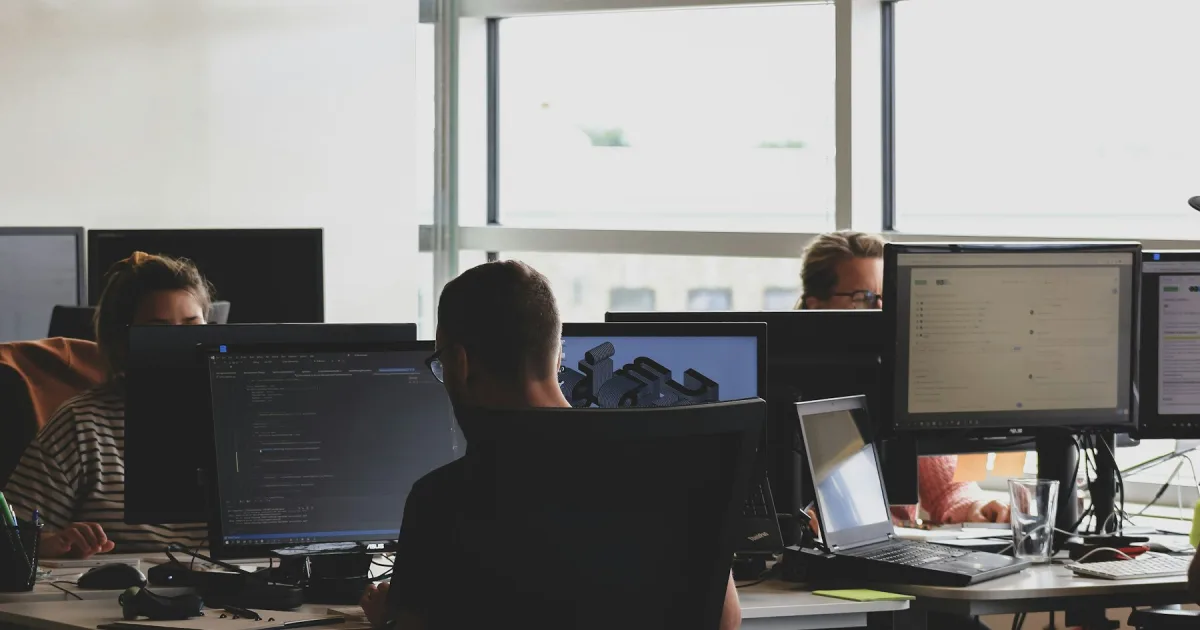 Two people looking at the same computer screen at a desk