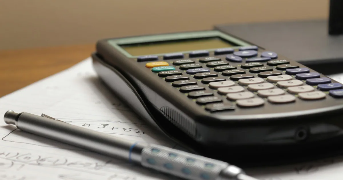 A calculator and pen resting on a sheet of figures