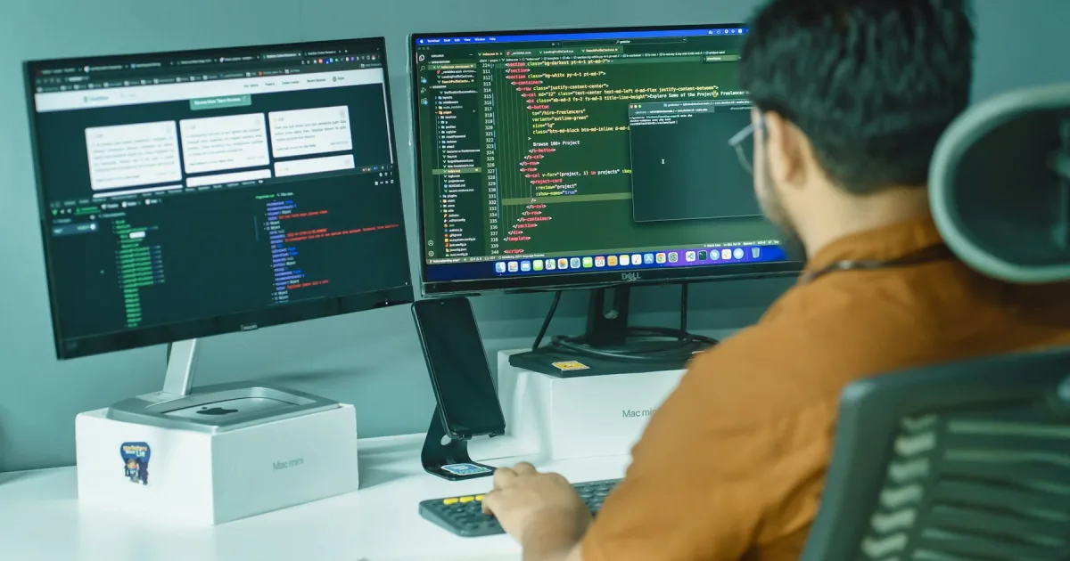 Someone at a desk working across two computer monitors